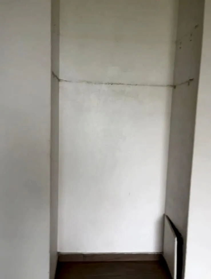 Niche vide aux murs blancs, sol en carrelage imitation bois, avant le chantier