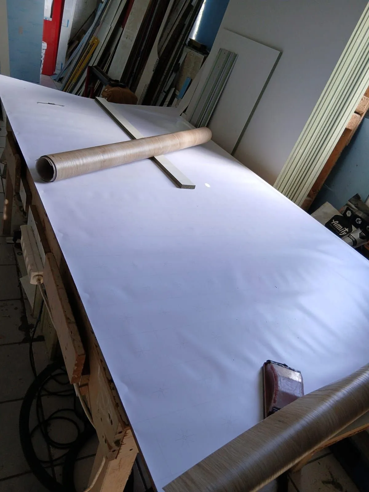 Film blanc déroulé sur un panneau, sur l'établi de l'atelier
