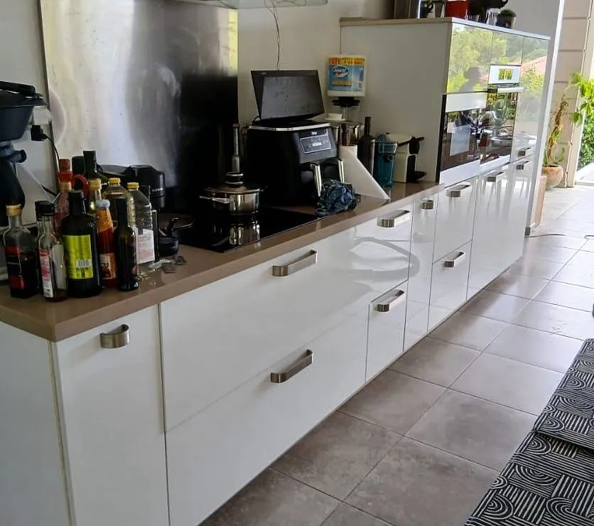 Linéaire de cuisine aux façades blanches à poignées métal, plan de travail bois